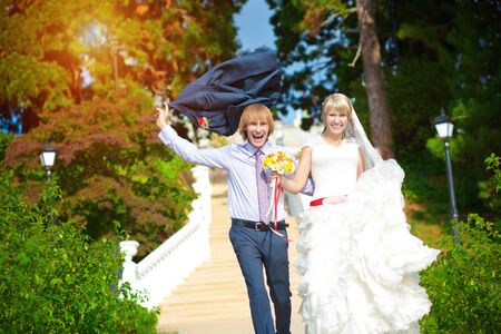 happy bride and groom are walking in the green parkの写真素材