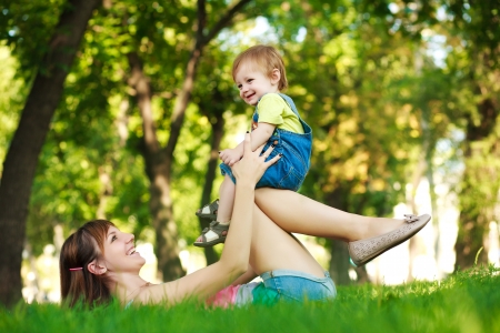 funny baby with mom in a greenl summer parkの写真素材