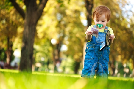 happy baby playing with a wallet in the green parkの写真素材