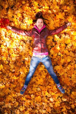 pretty girl is lying in yellow leavesの写真素材