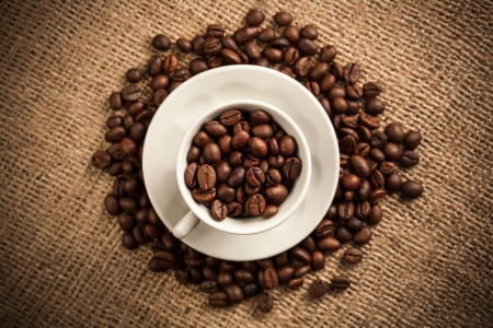 Roasted coffee beans in a cup on burlap backgroundの写真素材