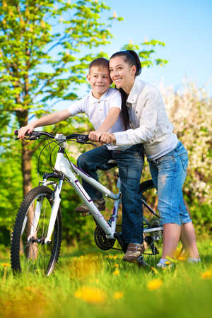 happy mom and son in a green park with a bikeの写真素材
