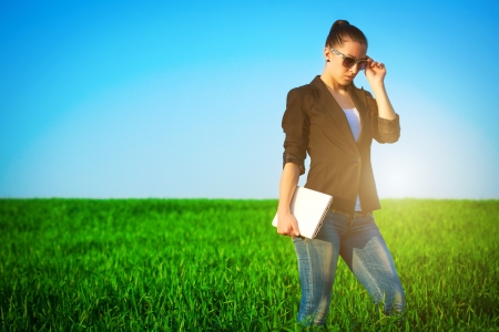 sexy businesswoman in a green field with a laptop  ideaの写真素材