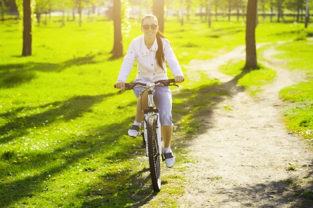 girl in a green park on a bikeの写真素材