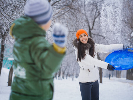 happy mother and son playing with snowballsの写真素材