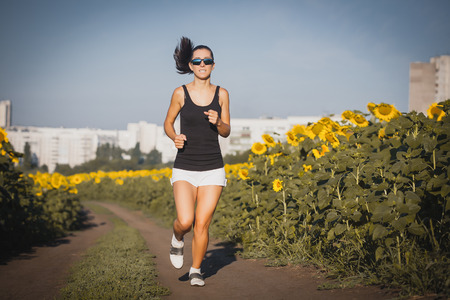 Young lady running on a rural road during sunsetの写真素材