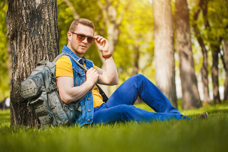 Handsome man sitting on the green grass in the parkの写真素材