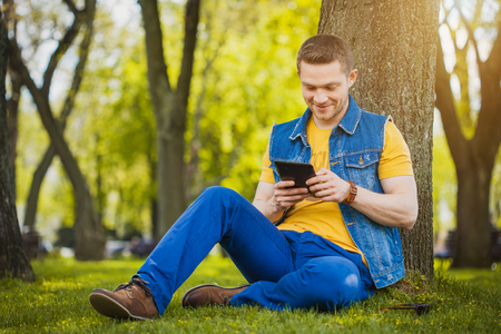 young man in blue shirt with tablet in the parkの写真素材