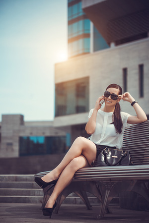 The beautiful young city woman sits on a benchの写真素材