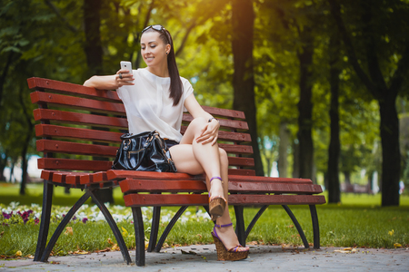 cute Young Woman with smartphone in the parkの写真素材