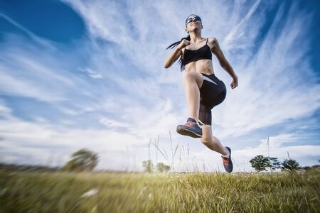 Young woman jogging in the summer parkの写真素材