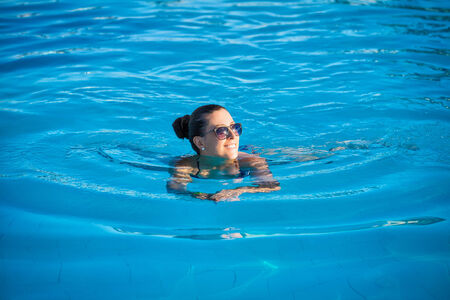 Woman relaxing near blue swimming poolの写真素材