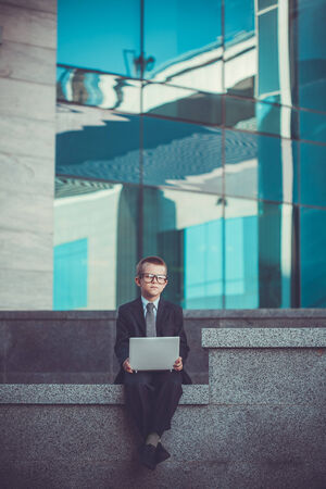 kid businessman with laptop on the blue modern backgroundの写真素材