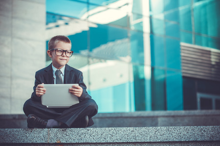 kid businessman with laptop on the blue modern backgroundの写真素材