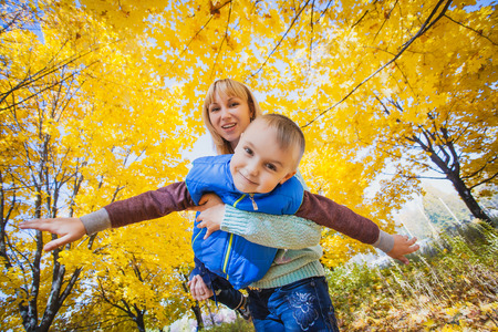 Young mother and her kid have fun in the autumn parkの写真素材