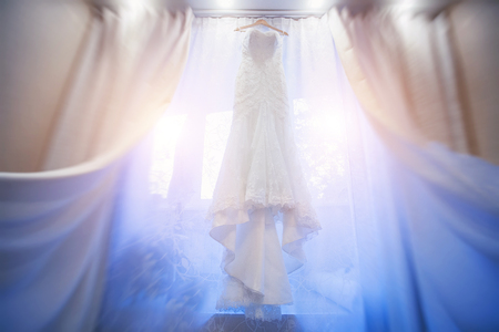 Wedding dress hanging in a window.の写真素材
