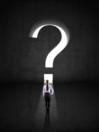 businesswoman against black wall with question mark holeの写真素材