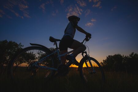 cyclist riding bike at sunsetの写真素材