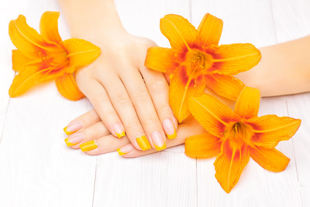 beautiful french manicure with orange lily flowersの写真素材