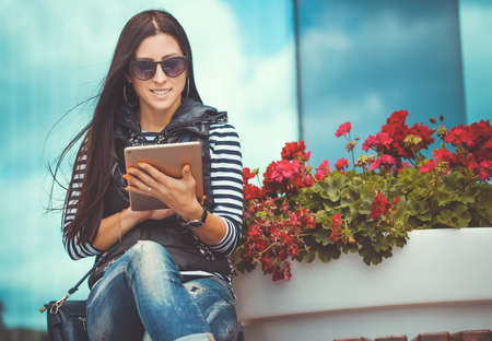 pretty woman with tablet is walking in the downtownの写真素材