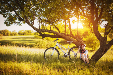 young Cyclist woman resting under a treeの写真素材