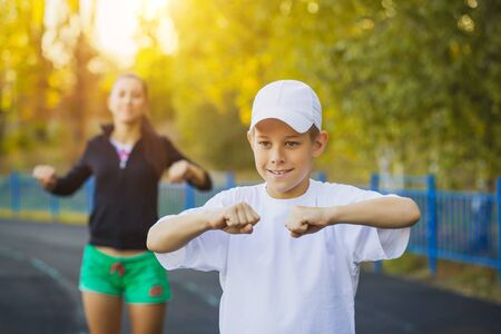 happy son and mother are doing exercises on the stadiumの写真素材