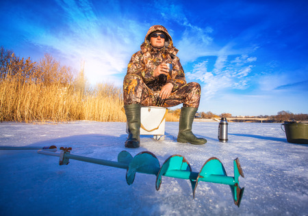Fisherman on a lake at winter sunny dayの写真素材