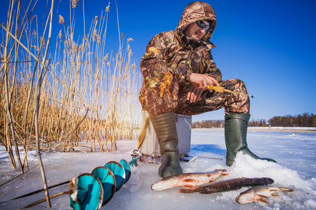 Happy ice fisherman holding a pike caught on a tip upの写真素材