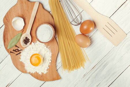 Pasta spaghetti with flour, egg and pepper on the white rustic wooden backgroundの写真素材