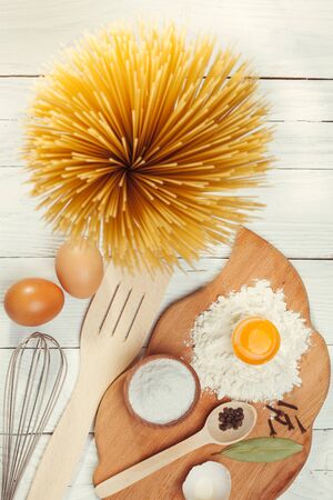 Pasta spaghetti with flour, egg and pepper on the white rustic wooden backgroundの写真素材
