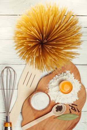 Pasta spaghetti with flour, egg and pepper on the white rustic wooden backgroundの写真素材