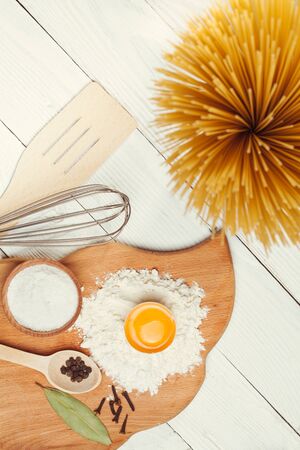 Pasta spaghetti with flour, egg and pepper on the white rustic wooden backgroundの写真素材
