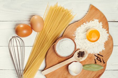 Pasta spaghetti with flour, egg and pepper on the white rustic wooden backgroundの写真素材
