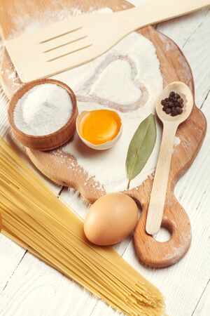 Pasta spaghetti with flour, egg and pepper on the white rustic wooden backgroundの写真素材