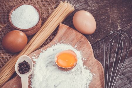 Pasta spaghetti with flour, egg and pepper on the old rustic wooden backgroundの写真素材