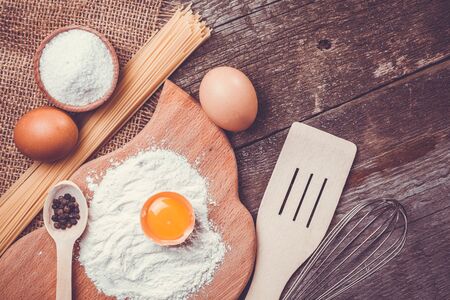 Pasta spaghetti with flour, egg and pepper on the old rustic wooden backgroundの写真素材