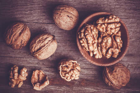 Walnut kernels and whole walnuts on old wooden tableの写真素材