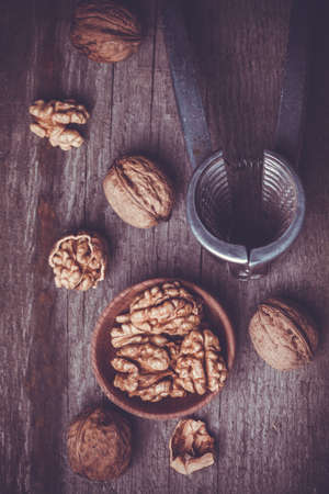 Walnut kernels and whole walnuts on old wooden tableの写真素材