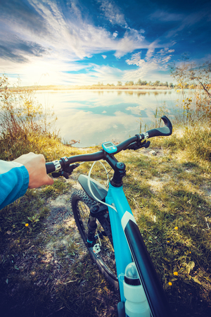 Man riding on a bicycle in summer near the lakeの写真素材