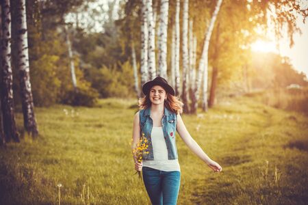Young happy girl in the park with flowersの写真素材