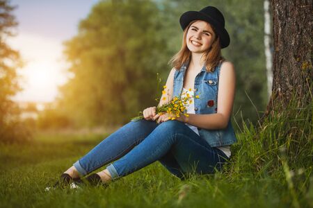 Young happy girl in the park with flowersの写真素材