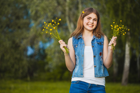 Young happy girl in the park with flowersの写真素材