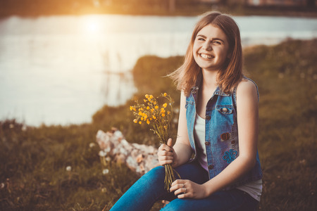 Young happy girl in the park with flowersの写真素材