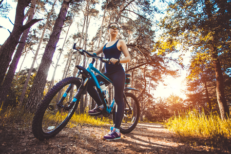 Happy woman cyclist rides in the forest on a mountain bike. Adventure travel. wide angleの写真素材