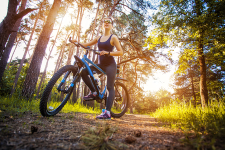 Happy woman cyclist rides in the forest on a mountain bike. Adventure travel. wide angleの写真素材
