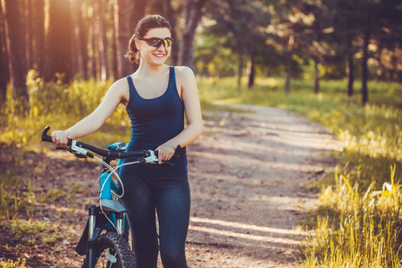 Happy woman cyclist rides in the forest on a mountain bike. Adventure travel. wide angleの写真素材