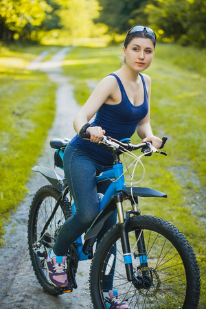 Happy woman cyclist rides in the forest on a mountain bike. Adventure travel. wide angleの写真素材
