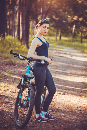 Happy woman cyclist rides in the forest on a mountain bike. Adventure travel. wide angleの写真素材