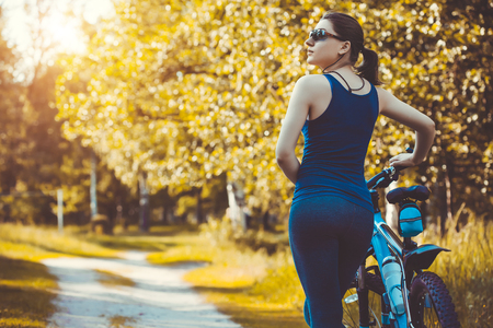 Happy woman cyclist rides in the forest on a mountain bike. Adventure travel. wide angleの写真素材