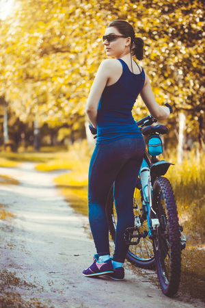 Happy woman cyclist rides in the forest on a mountain bike. Adventure travel. wide angleの写真素材
